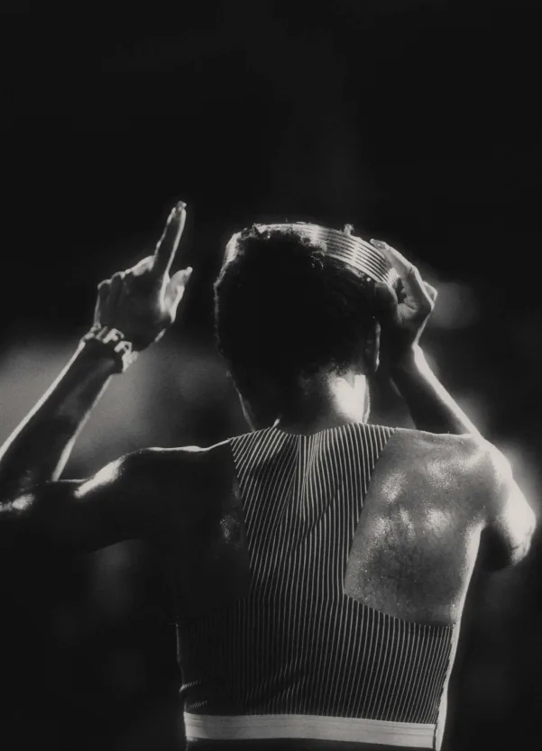 An athlete seen from behind, one finger raised and a crown on her head