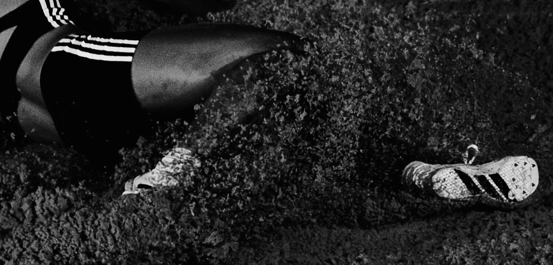 Black-and-white shot of an athlete's legs and spikes crossing the infield grass